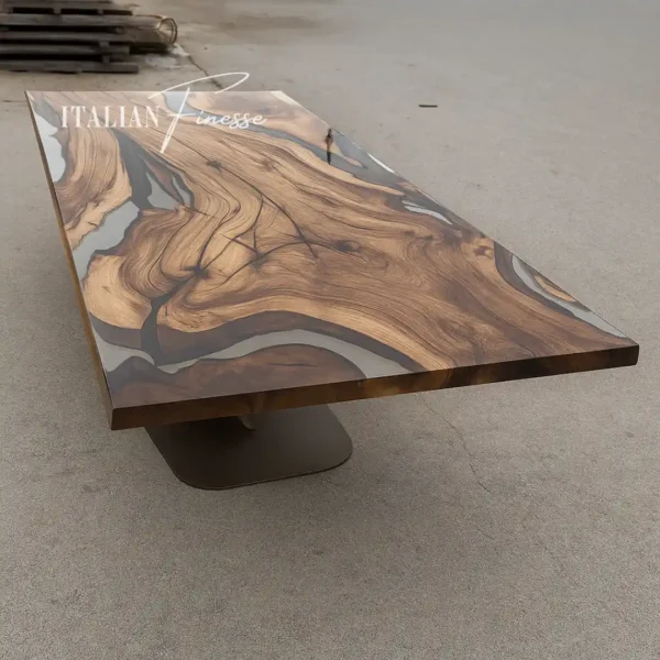 Tavolo rettangolare in legno di ulivo con venature marcate e inserti in resina grigia lucida, ambientato all’aperto su fondo neutro in cemento.