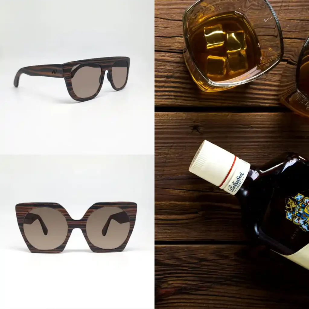 Occhiali da sole vintage artigianali in legno appoggiati su tavolo in legno con bicchieri di whiskey Ballantine’s – stile retrò e Made in Italy.